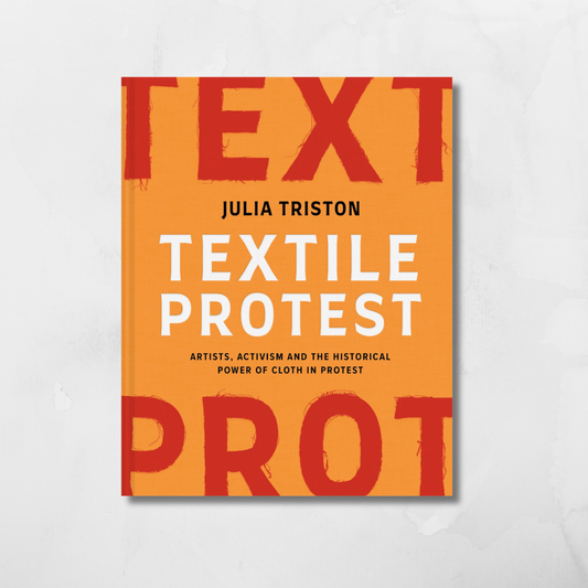 The book cover of 'Textile Protest' by Julia Tristan, featuring a bold orange background with large red and white typography, displayed on a light gray textured background.