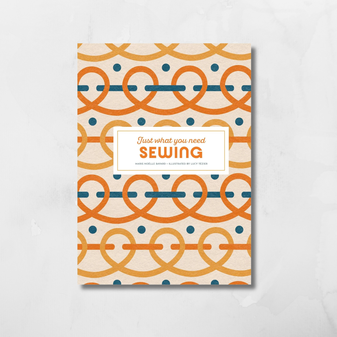 A vertical sewing pattern book cover featuring a cream background with orange and teal geometric patterns, centered on a light gray marble surface.