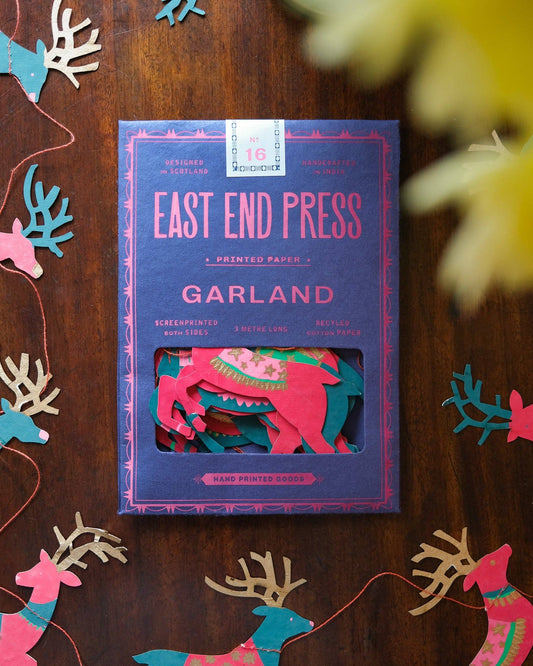 Box of 'Garland' printed paper by East End Press on a wooden surface with decorative cutouts.